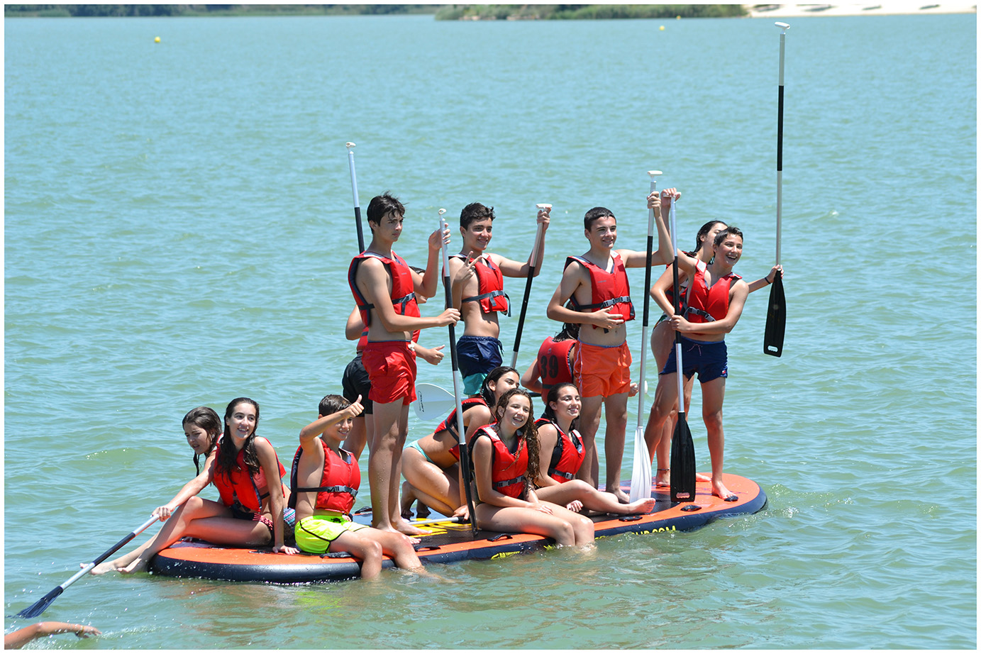 Grupo de niños y niñas en tabla de paddle surf colectiva